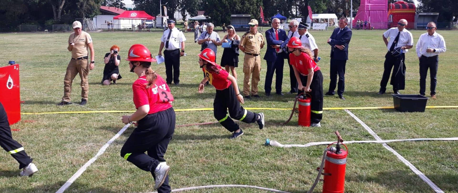 Powiatowe zawody sportowo-pożarnicze. Strażacy podczas zawodów sportowo-pożarniczych, sztafeta oraz ćwiczenie bojowe. 