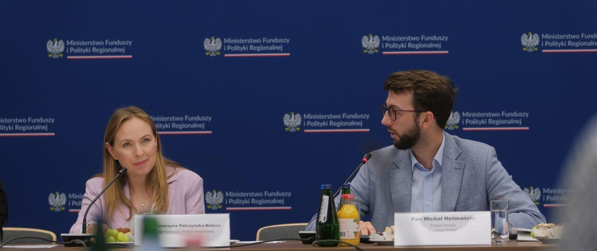 Dwie osoby siedzą obok siebie przy stole. Pierwsza od lewej siedzi minister Katarzyna Pełczyńska-Nałęcz.
