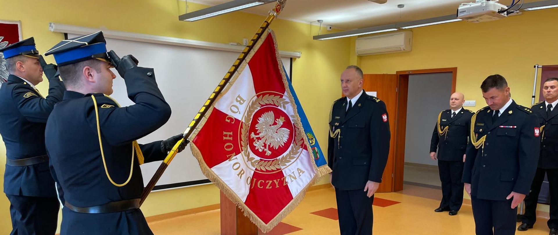 Komendant stoi na baczność przez Sztandarem