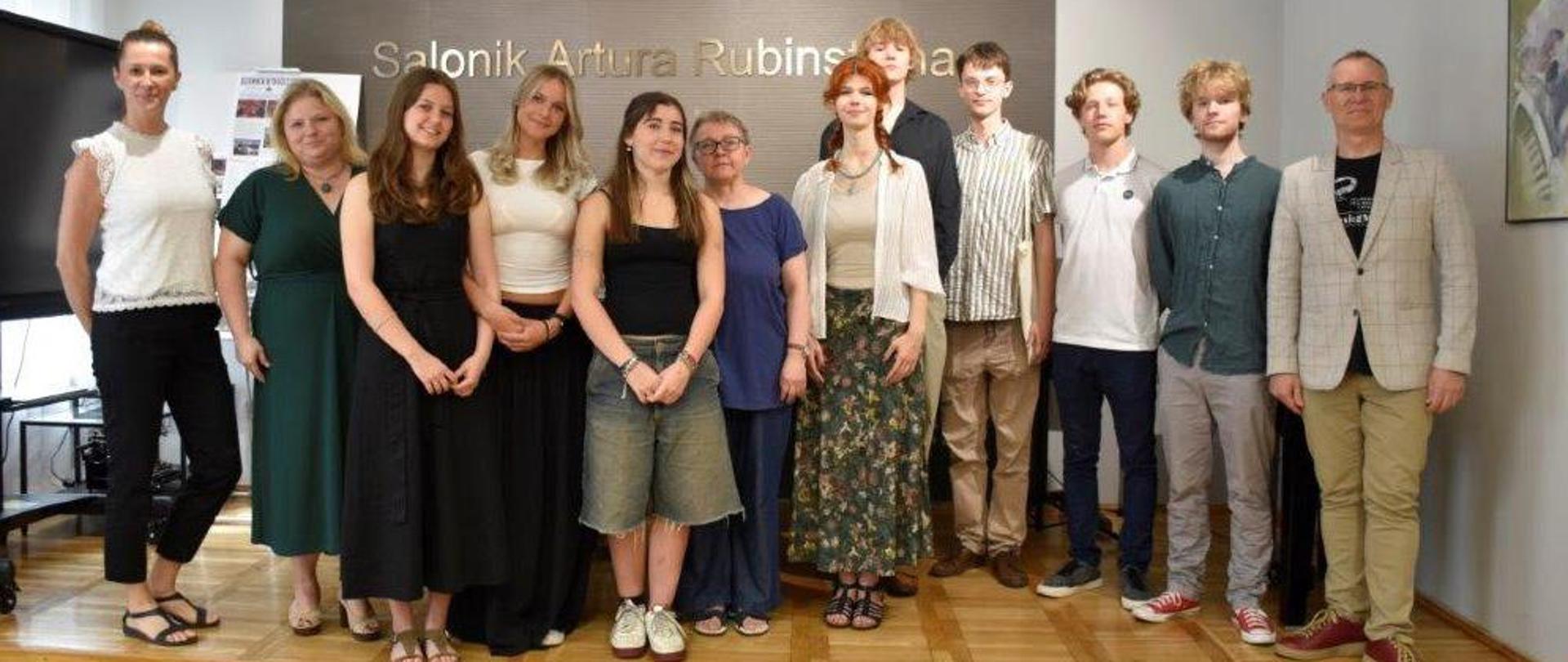 na zdjęciu na tle złotych liter salonik Artura Rubinsteina dyrekcja szkoły z maturzystami i nauczycielami 