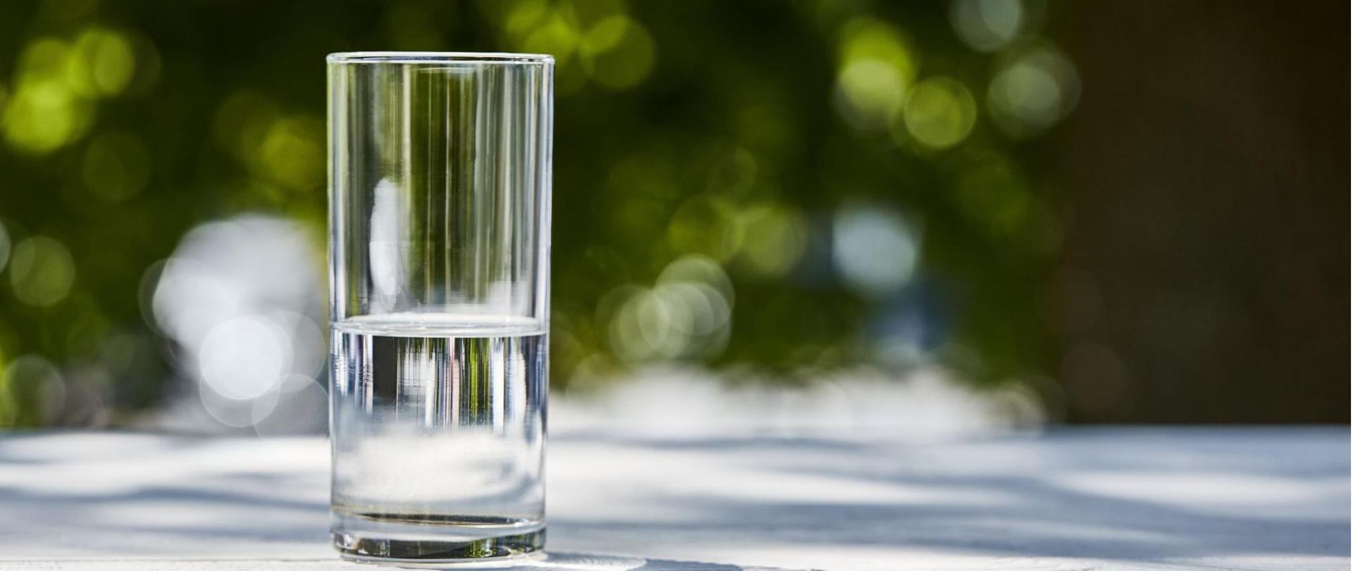 Na zdjęciu jest szklanka wody, która stoi na stole.