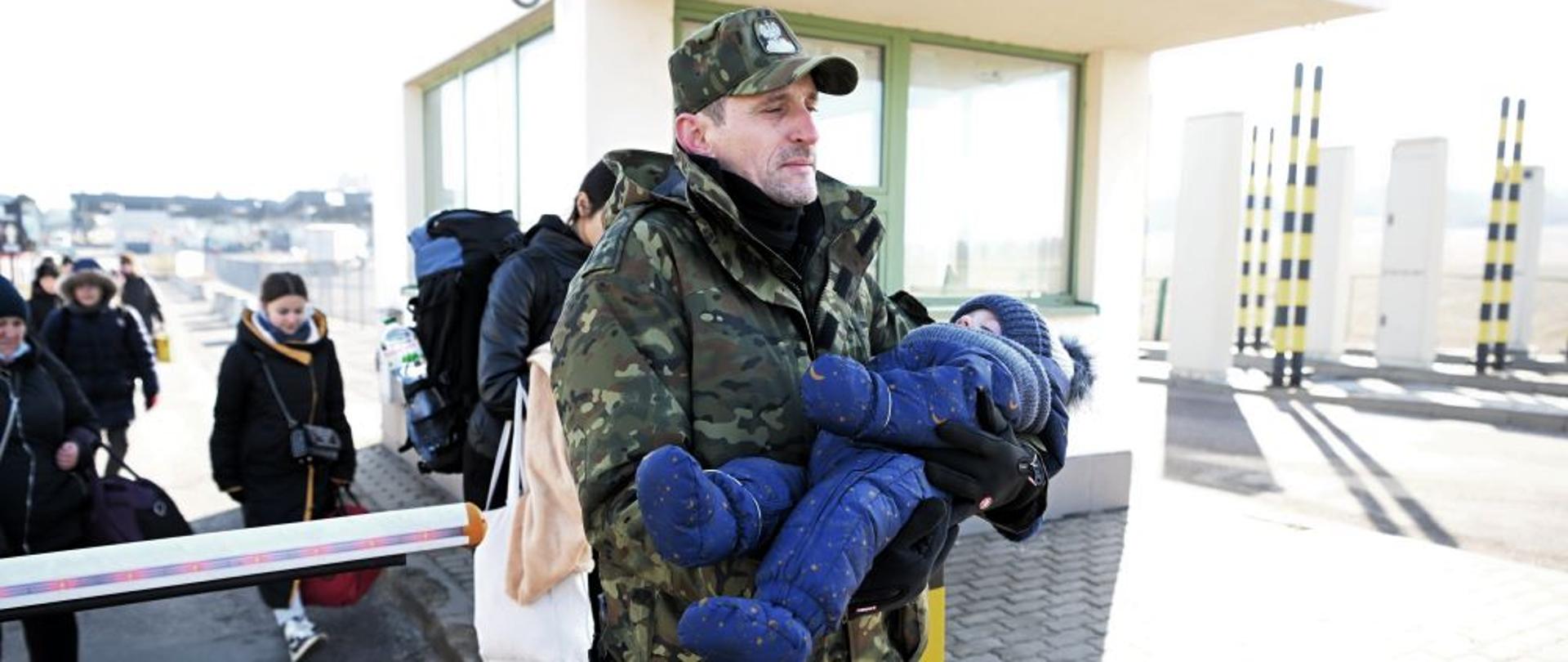 Funkcjonariusz Straży Granicznej pomaga uchodźcom z Ukrainy przejść granicę z Polską w Medyce. Pomocy w Polsce szukają głównie kobiety z dziećmi.
Fot. PAP/Darek Delmanowicz
