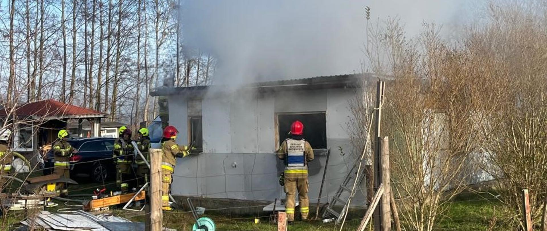 Barak mieszkalny objęty pożarem oraz strażacy