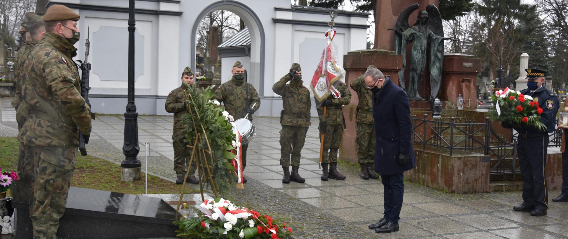 Na zdjęciu znajduje się mężczyzna składający wieniec