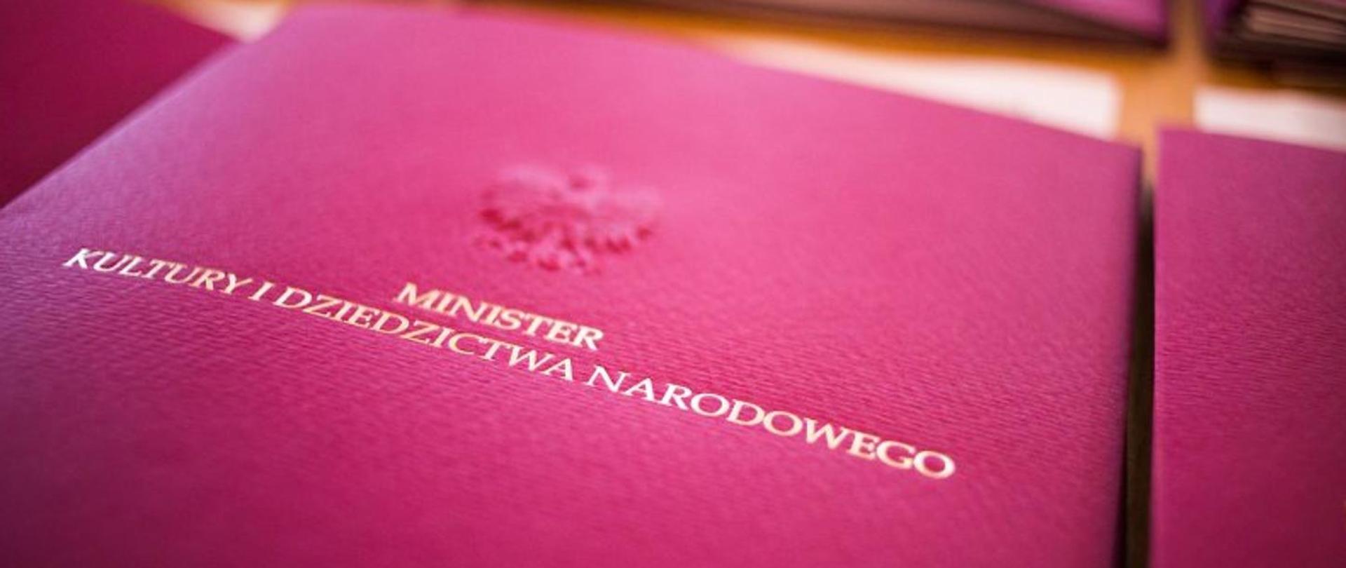 Fotografia bordowej papierowej teczki z napisem Minister Kultury i Dziedzictwa Narodowego w kolorze złotym, fotografia autorstwa Danuty Matloch