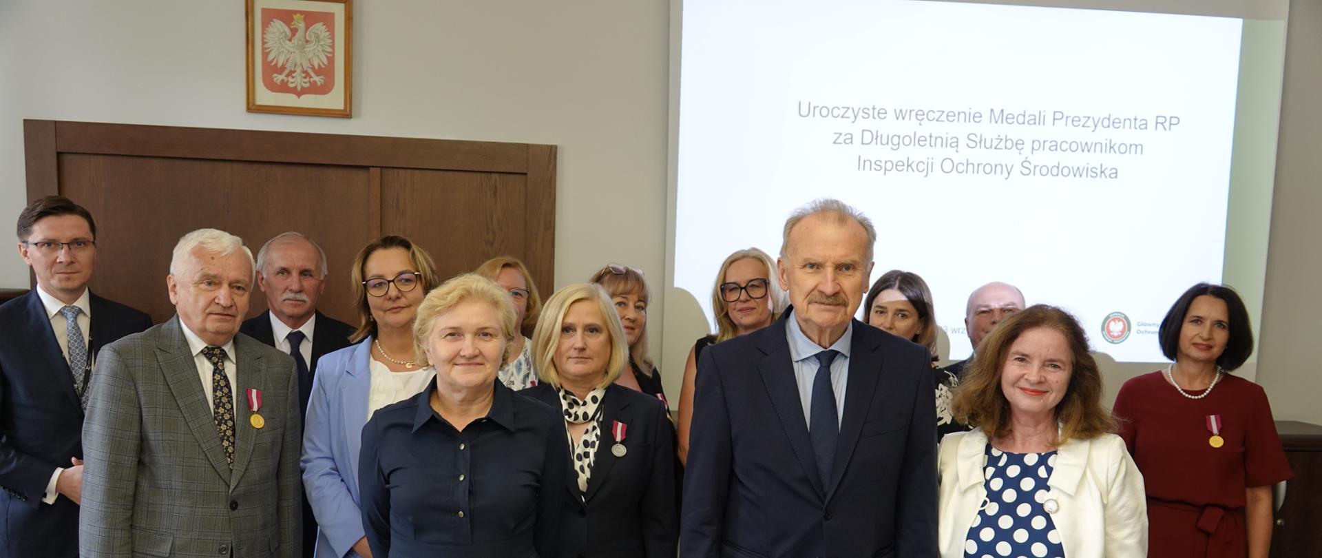 Kilkunastoosobowa grupa osób pozuje do pamiątkowego zdjęcia w związku z odznaczeniem ich Medalami Prezydenta RP za Długoletnią Służbę.