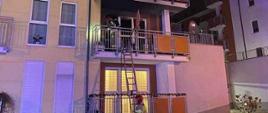 Na zdjęciu widzimy strażaków którzy przy użyciu drabiny dostali się na balkon w celu ugaszenia pożaru mieszkania.