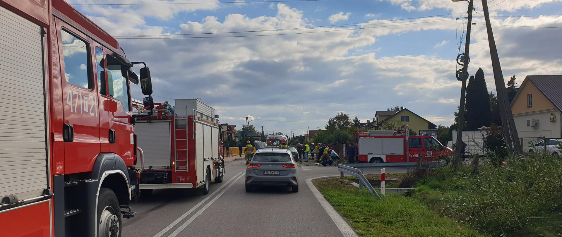 Zdjęcie przedstawia samochody ratowniczo-gaśnicze, w tle strażacy i rozbite samochody osobowe.