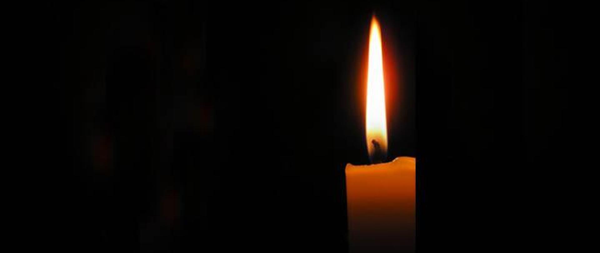 Grafika przedstawiająca paląca się świecę na czarnym tle