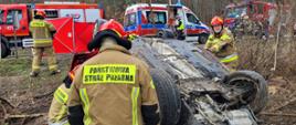 W tle widać, samochód biorący udział w zdarzeniu a także strażaków pracujących na miejscu zdarzenia