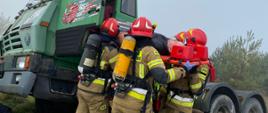 Strażacy udzielają pomocy poszkodowanemu kierowcy samochodu ciężarowego