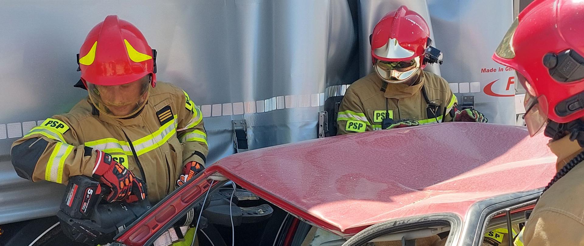 strażacy rozcinają samochód, żeby wyciągnąć poszkodowanych