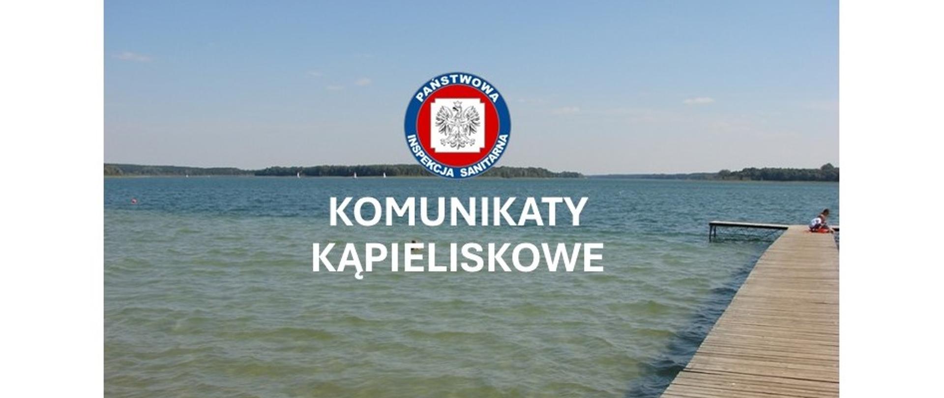 Jezioro z pomostem, logo Państwowej Inspekcji Sanitarnej, biały napis komunikaty kąpieliskowe