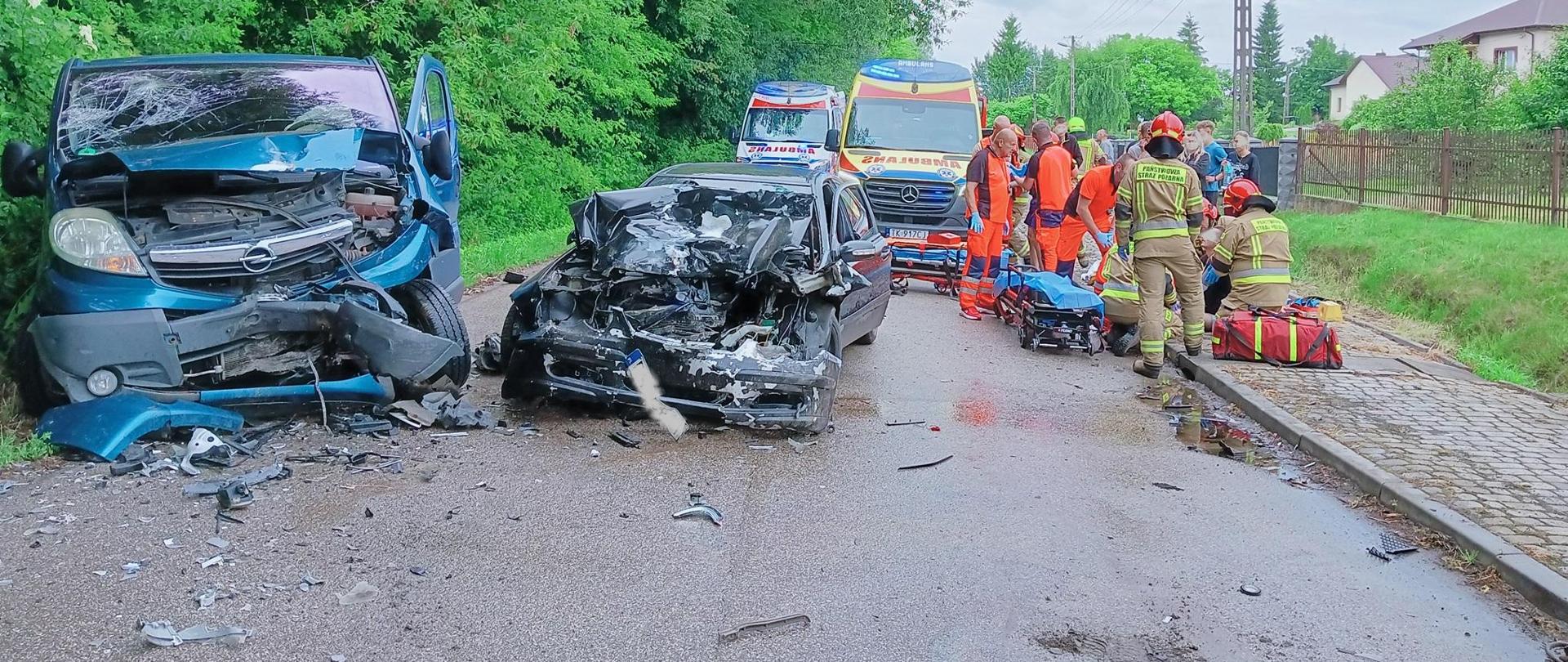 Na zdjęciu widoczne rozbite samochody i strażacy, ratownicy medyczni udzielający pomocy.