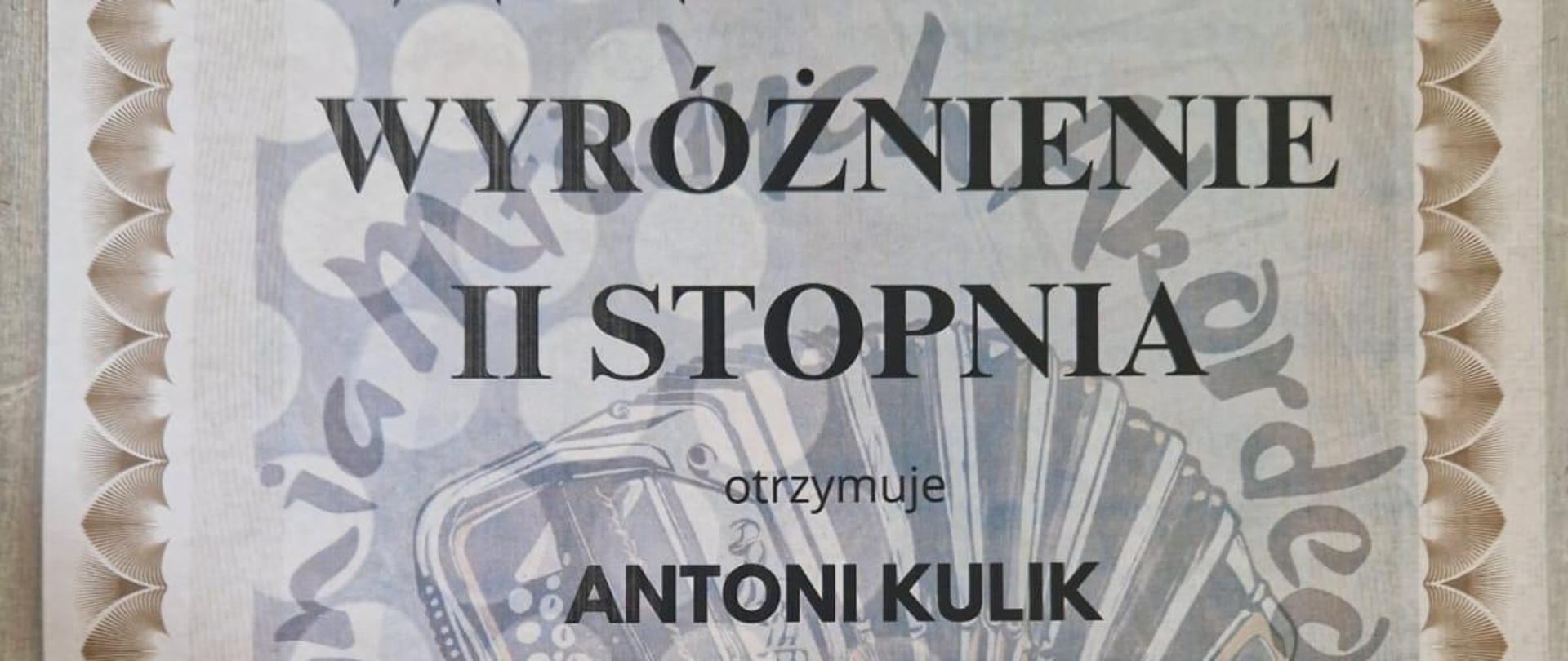 Dyplom uznania, który otrzymał Antoni Kulik za zajęcie wyróżnienia II stopnia podczas I Ogólnopolskich Spotkań Młodych Akordeonistów. Wydarzenie zostało zorganizowane przez Państwową Szkołę Muzyczną im. A. Tansmana w Łodzi. Antoni Kulik, uczeń Państwowej Szkoły Muzycznej I stopnia nr 1 w Kędzierzynie-Koźlu, uzyskał to wyróżnienie w kategorii I - klasa I cyklu sześcioletniego. Jego pedagogiem jest Ewa Rudzka-Sługocka. Dyplom został podpisany przez członków jury: dr Eneasz Kubit, dr hab. Grzegorz Palus oraz mgr Maciej Ćwikliński. Dokument datowany jest na 14 maja 2024 roku w Łodzi.