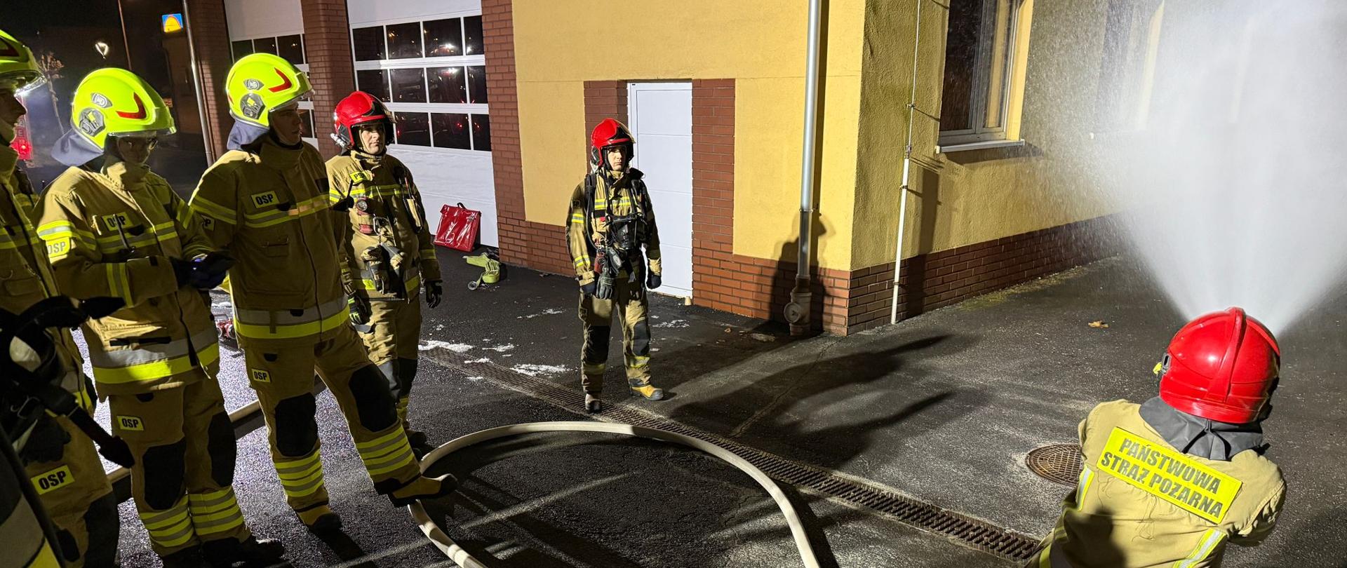 Na zdjęciu widoczni funkcjonariusze KP PSP w Oleśnie oraz druhowie OSP w umundurowaniu bojowym. Funkcjonariusz PSP przedstawia techniki operowania prądami gaśniczymi na placu komendy.