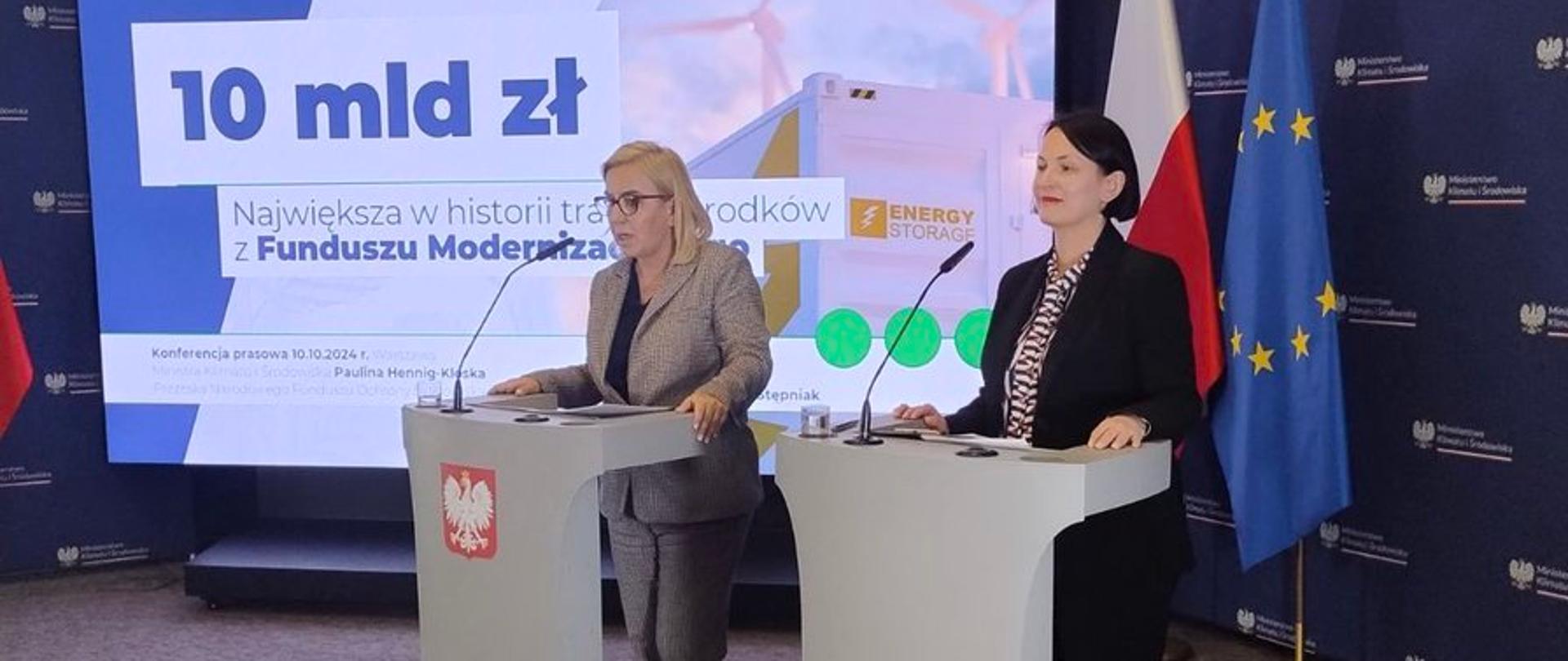 Zdjęcie z konferencji przedstawiające 2 stojące kobiety przy pulpitach mównic, od prawej: prezes zarządu NFOŚiGW Dorota Zawadzka-Stępniak, minister klimatu i środowiska Paulina Hennig-Kloska