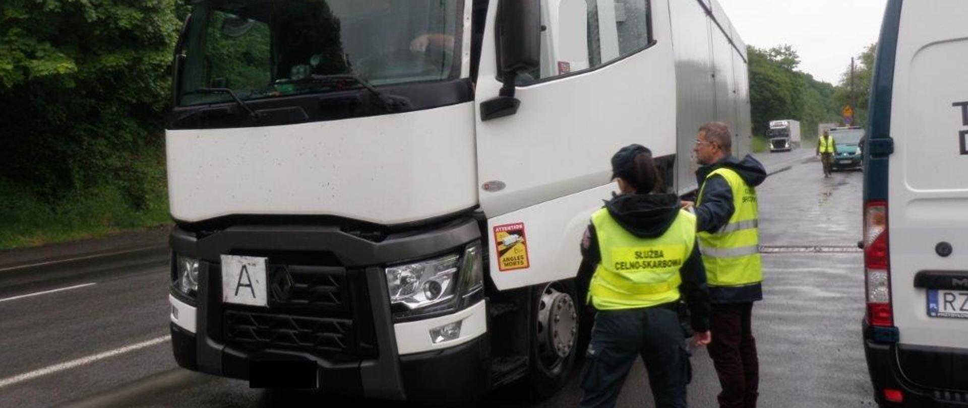 Pracownik Inspekcji Ochrony Środowiska i Służby Celnej stoją przy otwartych drzwiach kontrolowanej ciężarówki.