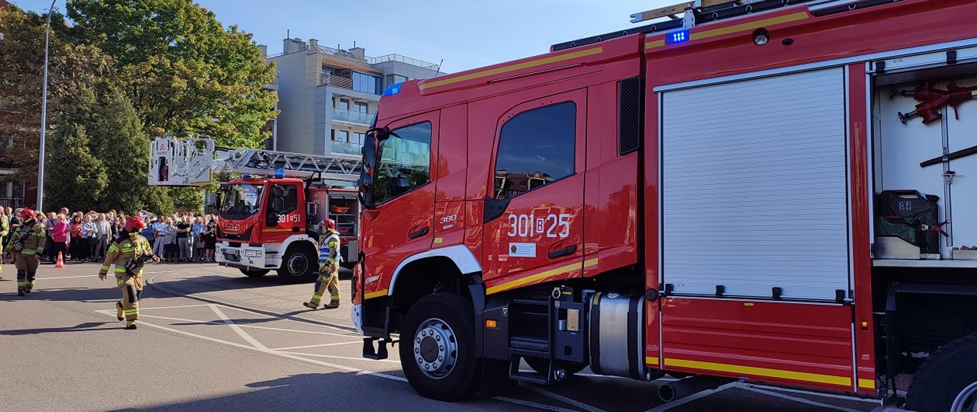 Strażacy podczas ćwiczeń, w tle ewakuowani pracownicy Urzędu Miejskiego