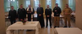 Ksiądz błogosławiący wigilijne opłatki, towarzyszą mu komendanci SA PSP w Krakowie, oraz strażacy z Jednostki Ratowniczo - Gaśniczej, jeden z nich trzyma lampion ze światełkiem pokoju 