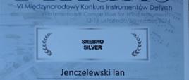 Dyplom w kolorze niebieskim. W nagłówku jest umieszczona nazwa konkursu, poniżej napis: srebro silver, Ian Jenczelewski. 