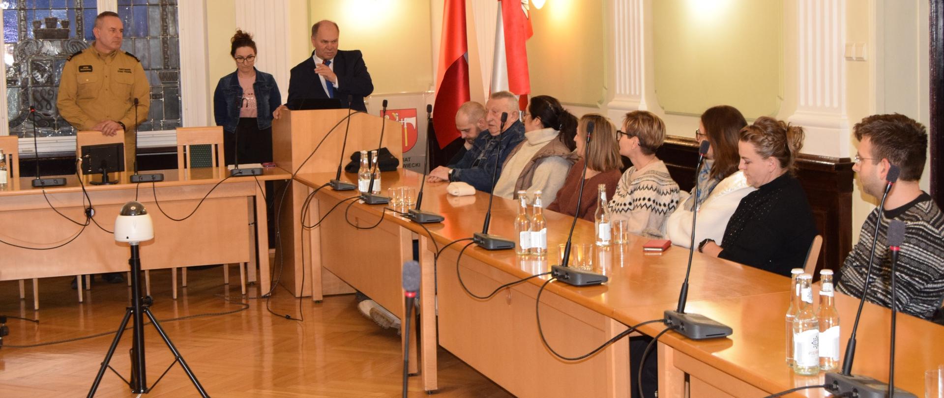 Na zdjęciu widać starostę, komendanta oraz mieszkańców w sali starostwa 