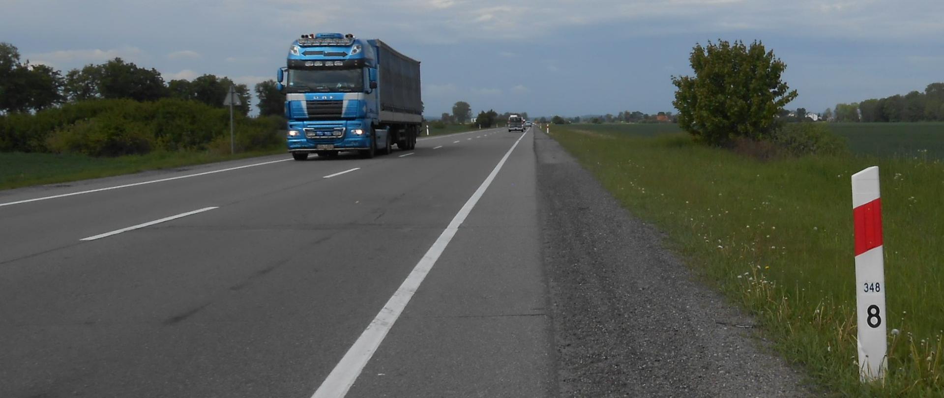 Zdjęciem przedstawia drogę krajową nr 22 między Knybawą a Gnojewem z poruszającymi się pojazdami. Po lewej stronie niewielkie zadrzewienie, po prawej pola uprawne.