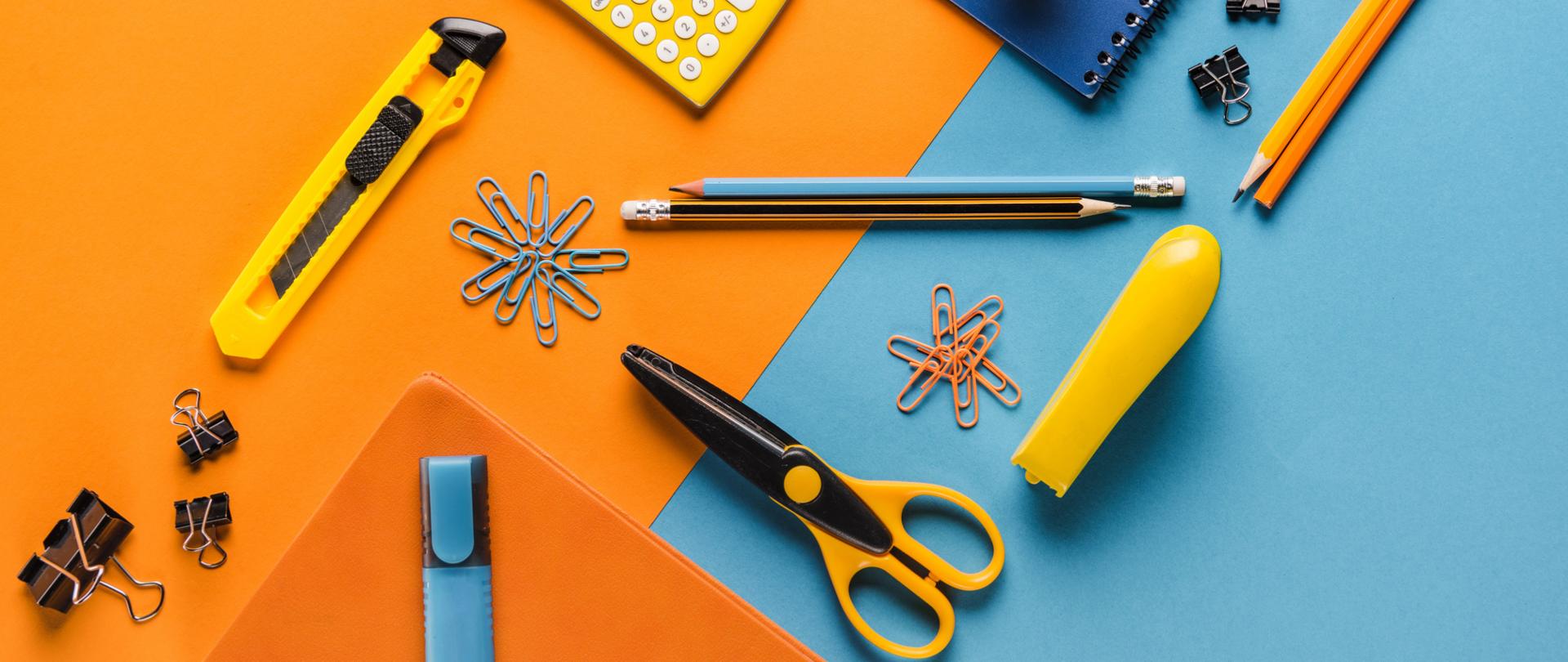 Na zdjęciu są przybory szkolne, np. ołówki, kalkulator, nożyczki itd. Tło jest pomarańczowo niebieskie.