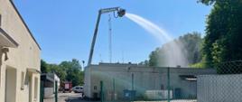 Zdjęcie przedstawia podawanie wody z kosza podnośnika strażackiego na budynek podczas ćwiczeń