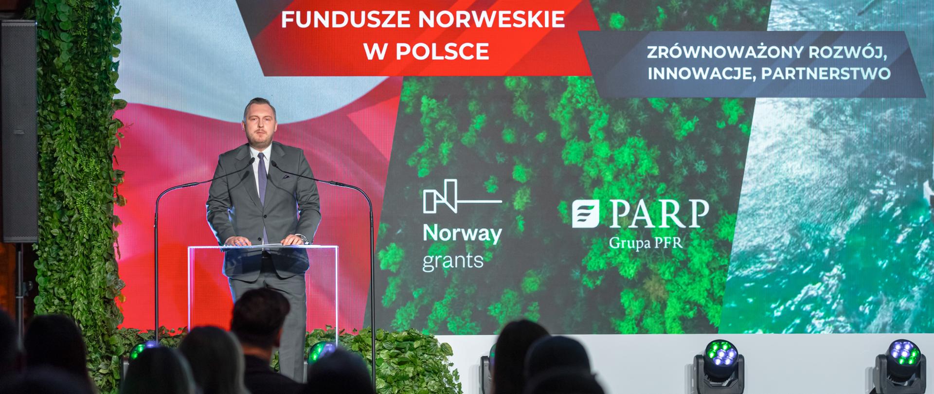 Na scenie wiceminister Konrad Wojnarowski w mównicy. Przed nim publiczność,