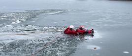 Na zdjęciu strażak przystępuje do ewakuacji, pozoranta pod któym załamał się lód na jeziorze.