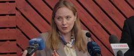 Minister Katarzyna Pełczyńska-Nałęcz stroi przy mikrofonach i rozmawia z dziennikarzami w Białowieży