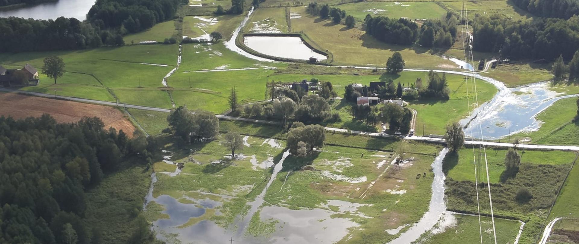 Zdjęcie przedstawia tereny zielone zalane wodą, krzewy, łąki z lotu ptaka.