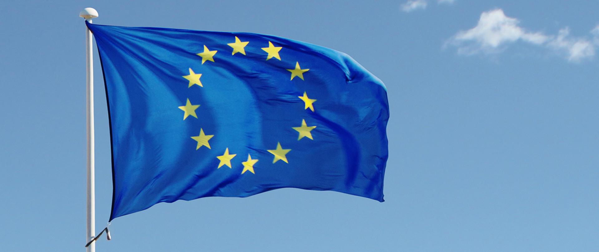 Wisząca flaga Unii Europejskiej na tle nieba 