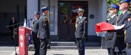 Na zdjęciu w mundurze galowym Warmińsko mazurski Komendant Wojewódzki. Przyjmuje meldunek o gotowości do uroczystości. Obok stoją funkcjonariusze w mundurach galowych.