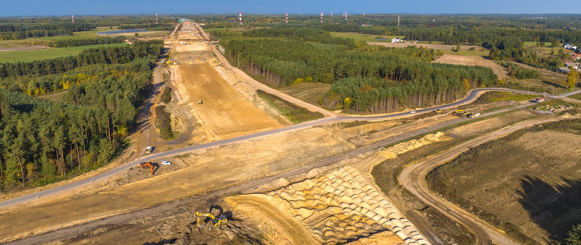 Widok z lotu ptaka na budowę autostrady A2. Słoneczny dzień, widać już zarys przyszłej drogi.