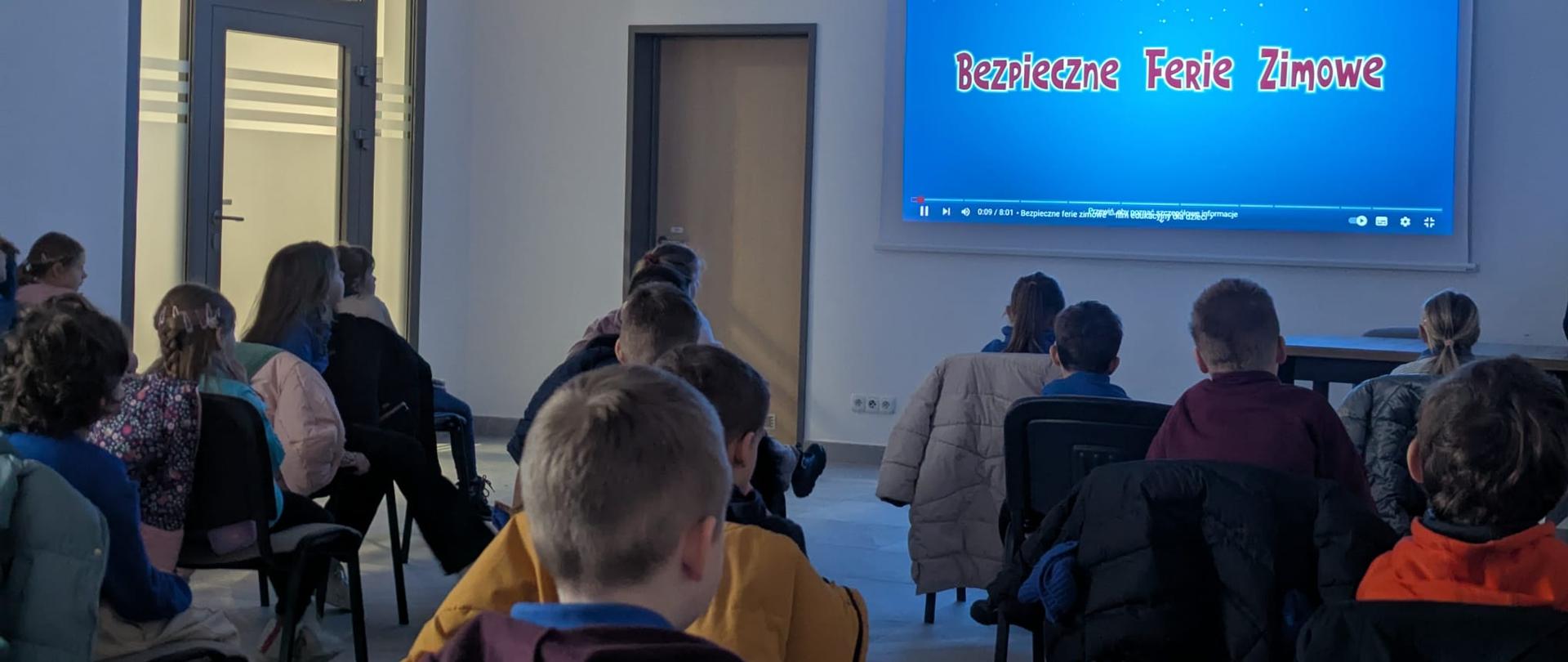 Młodzież szkolna, ogląda dedykowaną prezentację dotyczącą bezpieczeństwa podczas freii zimowych na sali szkoleniowej w jednostce ratowniczo- gaśniczej.