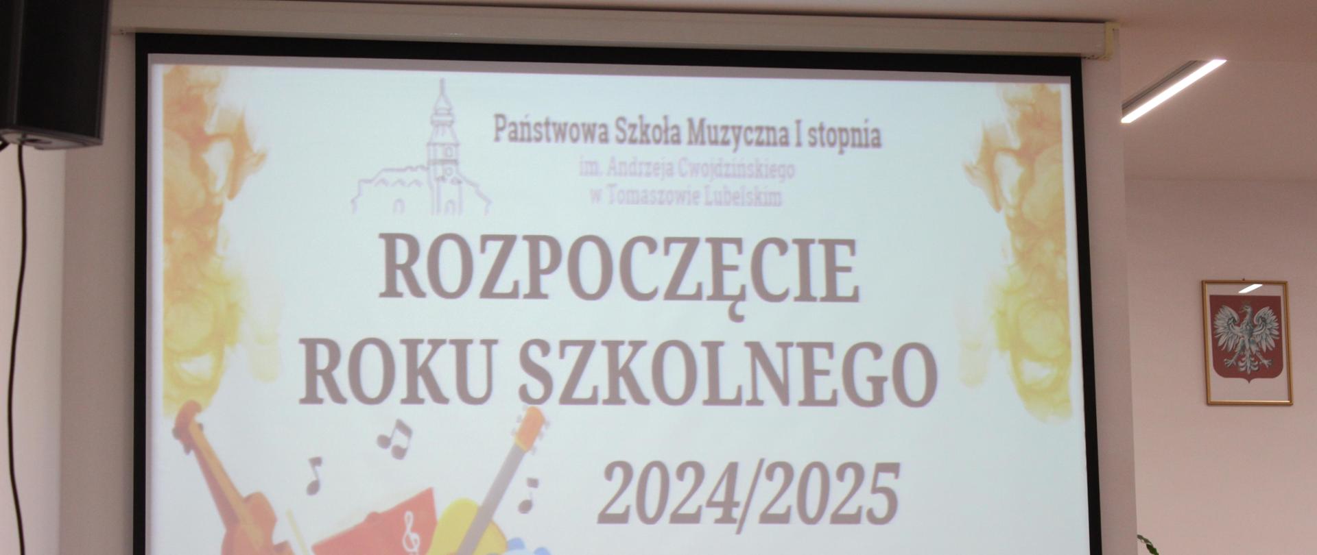 na zdjęciu projektor z wyświetlanym plakatem na którym widać instrumenty muzyczne, nutki na falującej pięciolinii, logo szkoły oraz napisy informujące o rozpoczęciu roku szkolnego