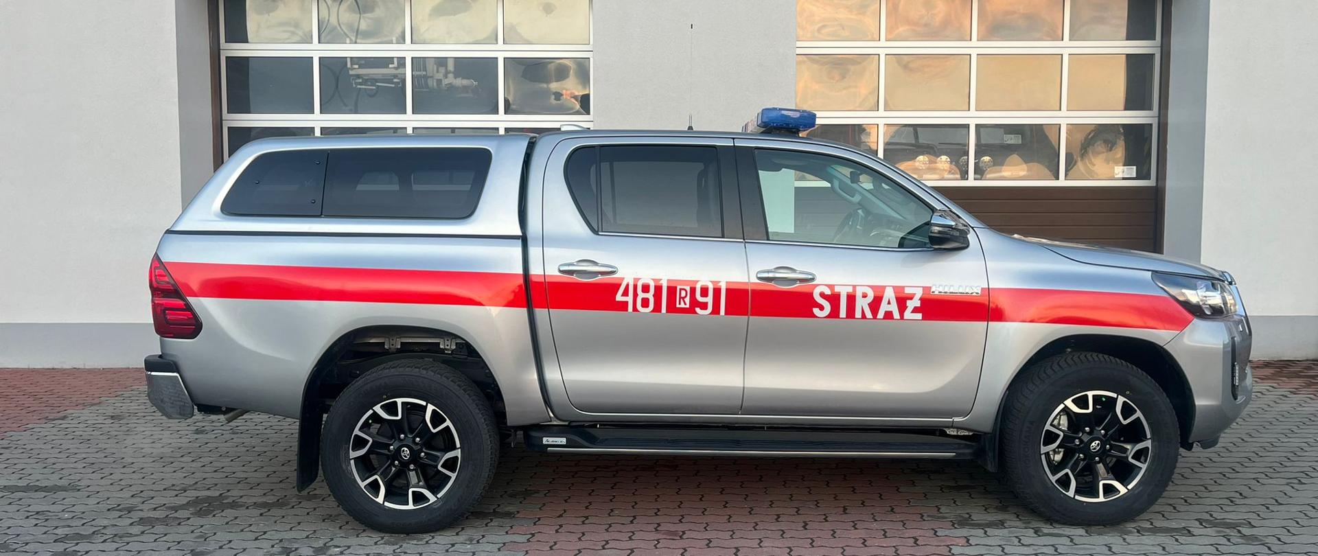 zdjęcie przedstawia samochód rozpoznawczo-ratowniczy Toyota HiLux na tle budynku