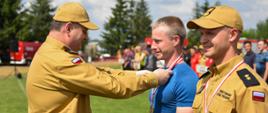 starszy brygadier Piotr Rudecki wiesza medal na szyi zawodnika