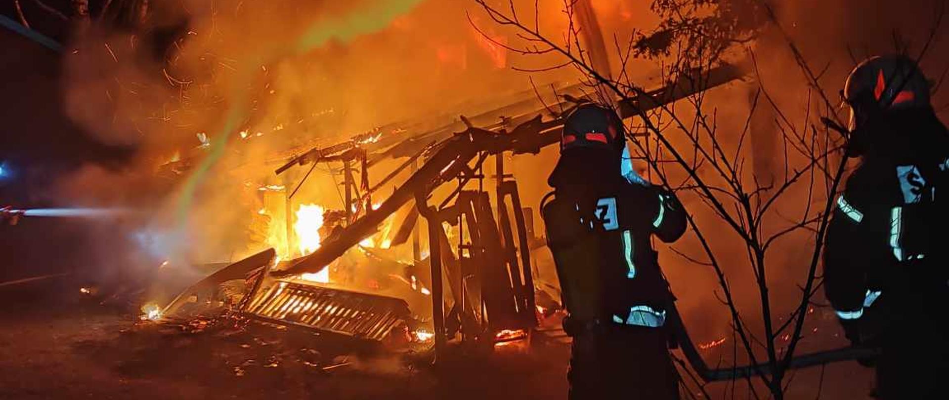 Na zdjęciu widać płonący budynek oraz strażaków gaszących pożar