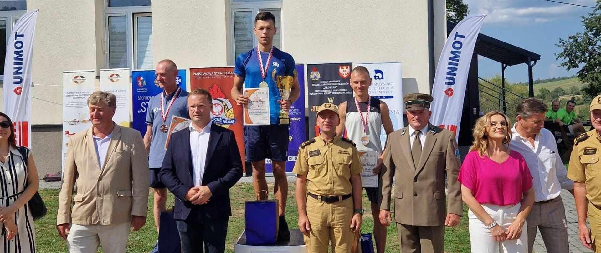 Na podium zwyciezcy, a pod podium osoby wreczające nagrody