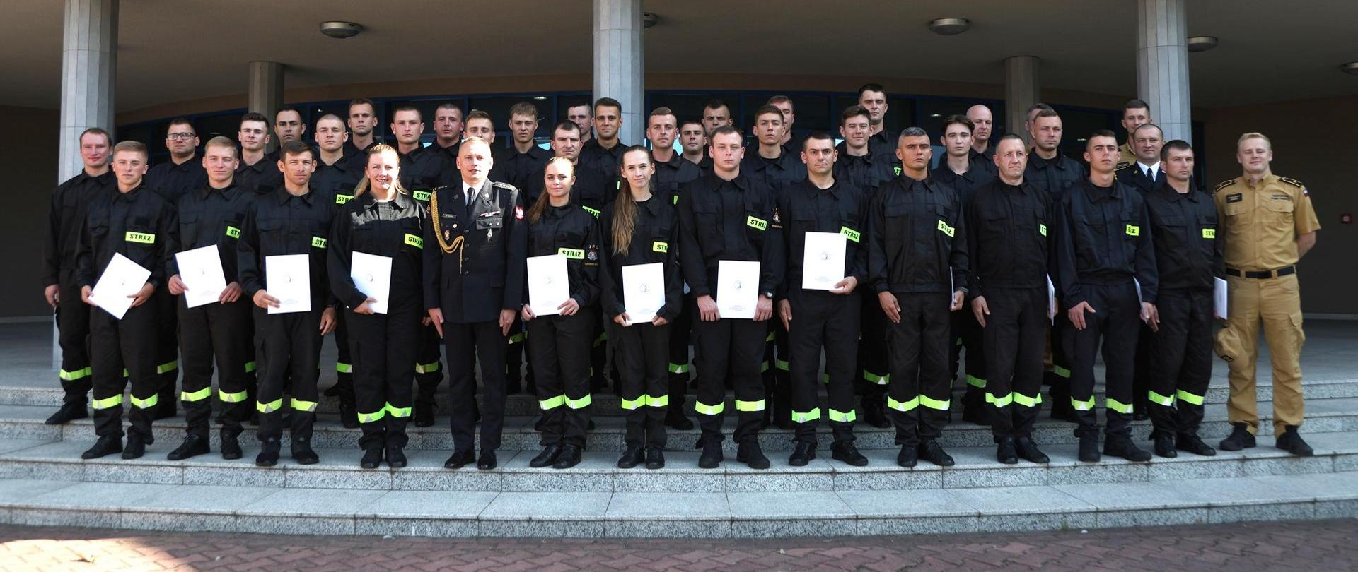 Pamiątkowe zdjęcie grupowe uczestników czwartego turnusu szkolenia podstawowego w zawodzie strażak w towarzystwie Zastępcy Komendanta Centralnej Szkoły PSP oraz trzech funkcjonariuszy CS PSP