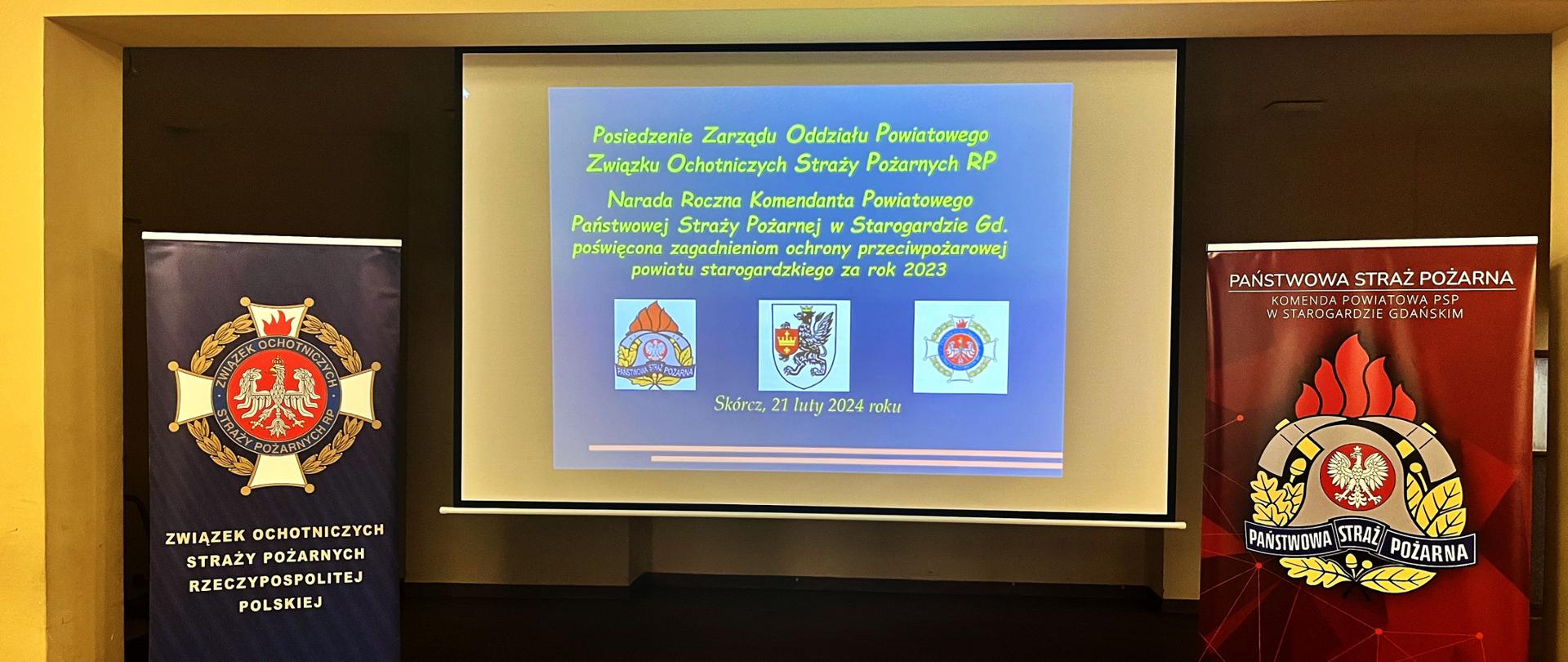 Zdjęcie przedstawia banery reklamowe Państwowej Straży Pożarnej, Zarządu Oddziału Powiatowego Związku Ochotniczych Straży Pożarnych RP oraz stronę z pokazu.