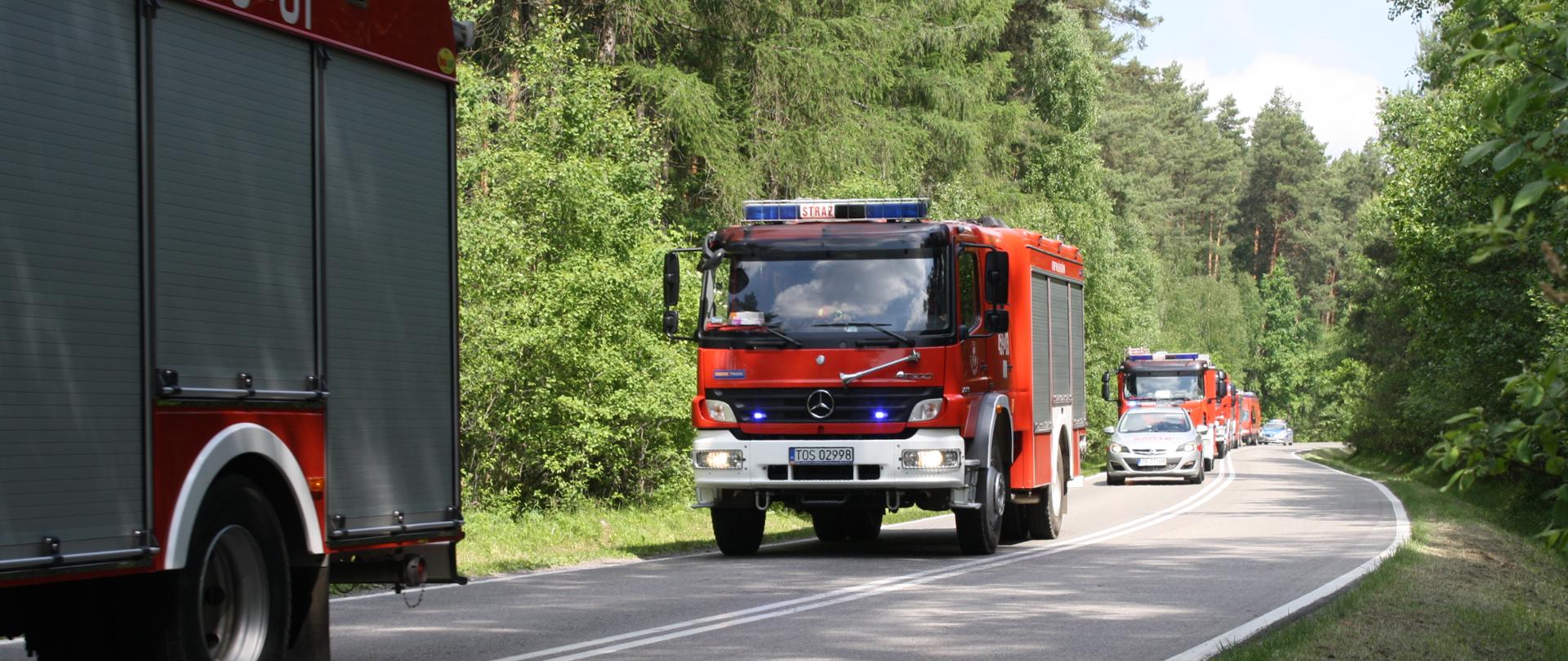 Kolumna pojazdów pożarniczych jadących ulicą na ćwiczenia
