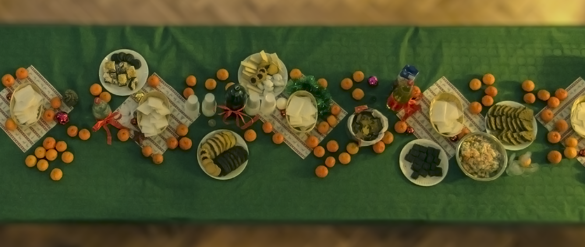Zdjęcie przedstawiające sfotografowany z góry stół z opłatkami, ciastami i mandarynkami