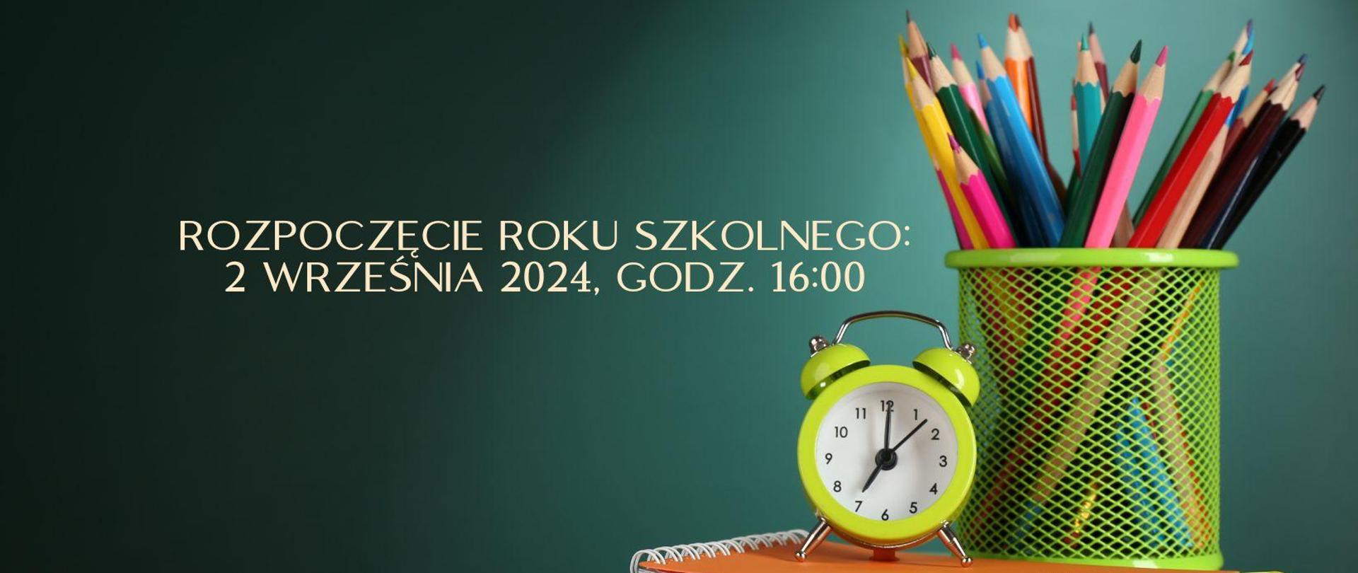 Na zielonym tle ściany blat biurka, a na nim po prawej stronie: książka, zeszyt kubek z włożonymi w niego kolorowymi kredkami i budzik, po lewej: napis z informacją o dacie i godzinie rozpoczęcia roku szkolnego.