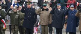 Reprezentant Straży Miejskiej, Wojska, Straży Pożarnej oraz Policji stoją na baczność i salutują.