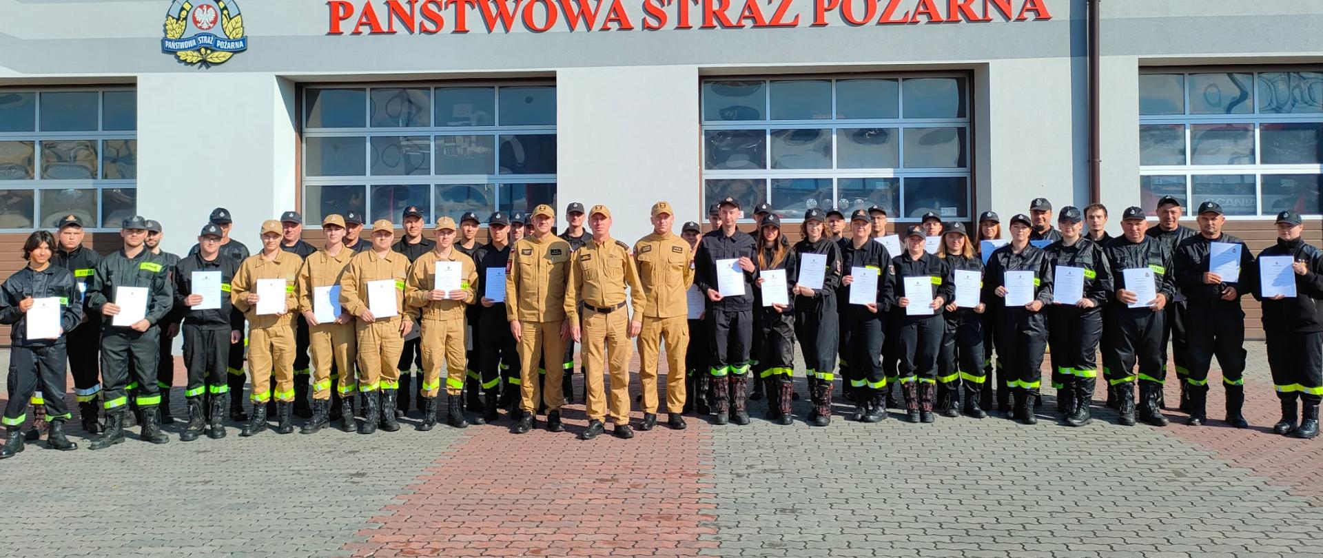 na pierwszym planie uczestnicy szkolenia ustawieni przed budynkiem KP PSP Lubaczów, w tle budynek z logo oraz napis Państwowa Straż Pożarna