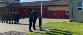 Funkcjonariusze Komendy Powiatowej Państwowej Straży Pożarnej w Rypinie oddają honor w kierunku Flagi Państwowej, która została wciągnięta na maszt znajdujący się na placu Jednostki Ratowniczo-Gaśniczej.